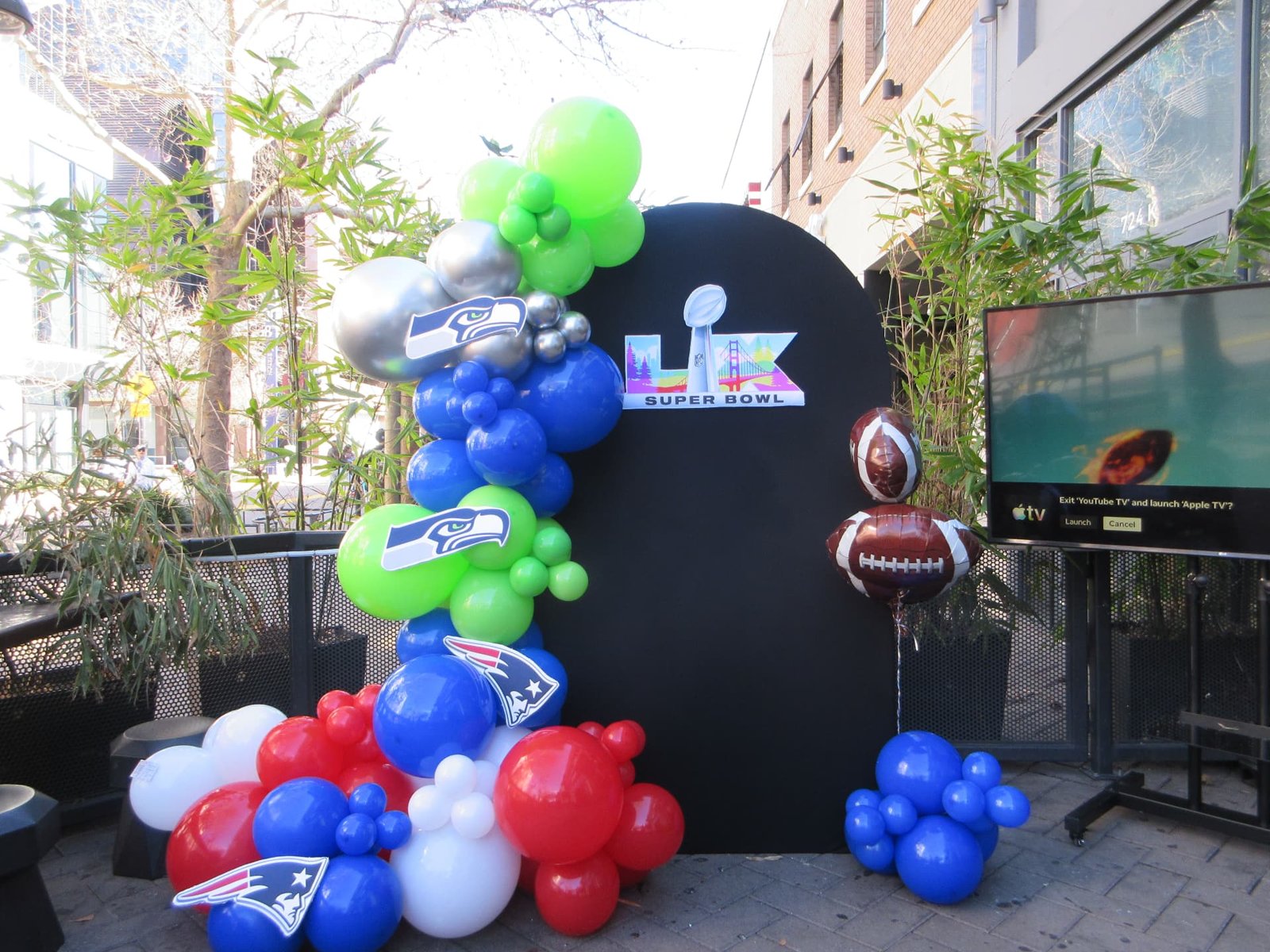 Super Bowl themed balloon garland on a black arch backdrop with football balloons