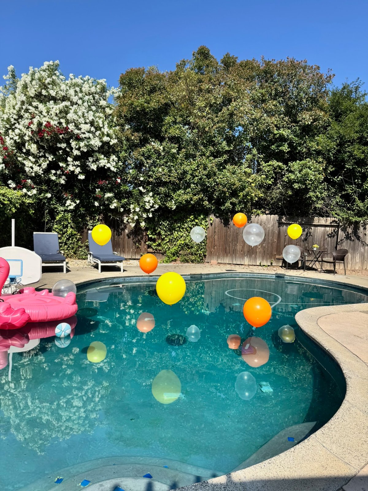 Yellow, orange and clear floating balloons styling a backyard pool party