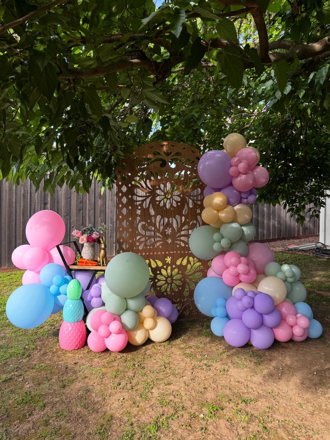 Pastel balloon garland with a carved wood backdrop outdoors