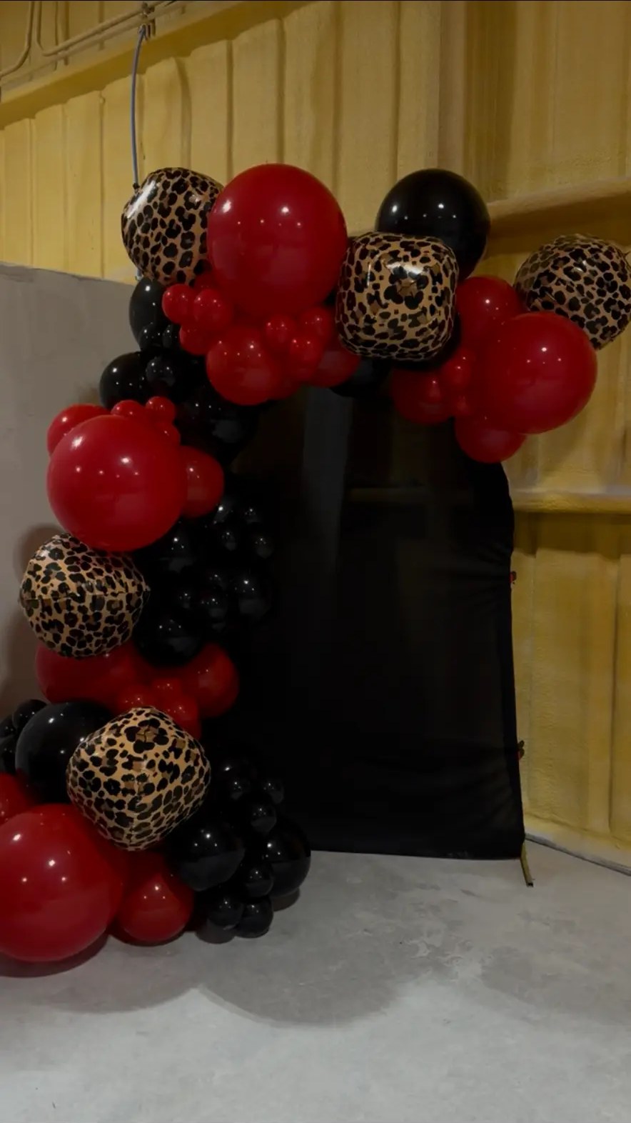 Red, black and leopard print balloon garland on a black backdrop